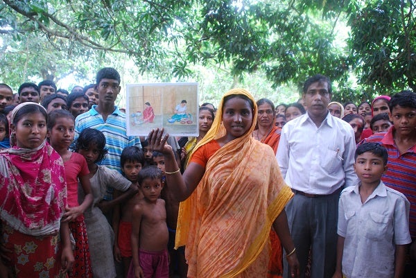 Woman holding up book with crowd behind