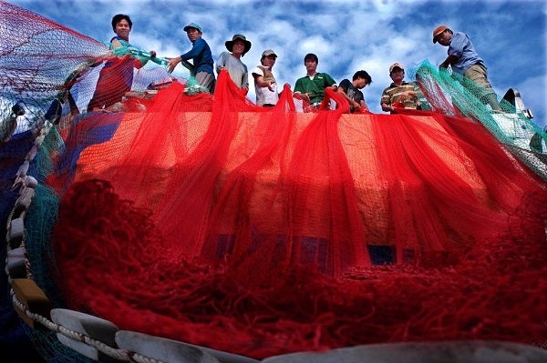 Men prepare for a voyage by adjusting nets.